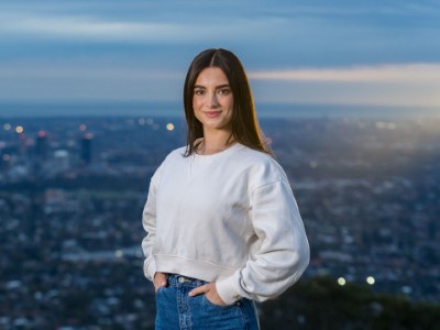 Student standing in front of Adelaide city skyline